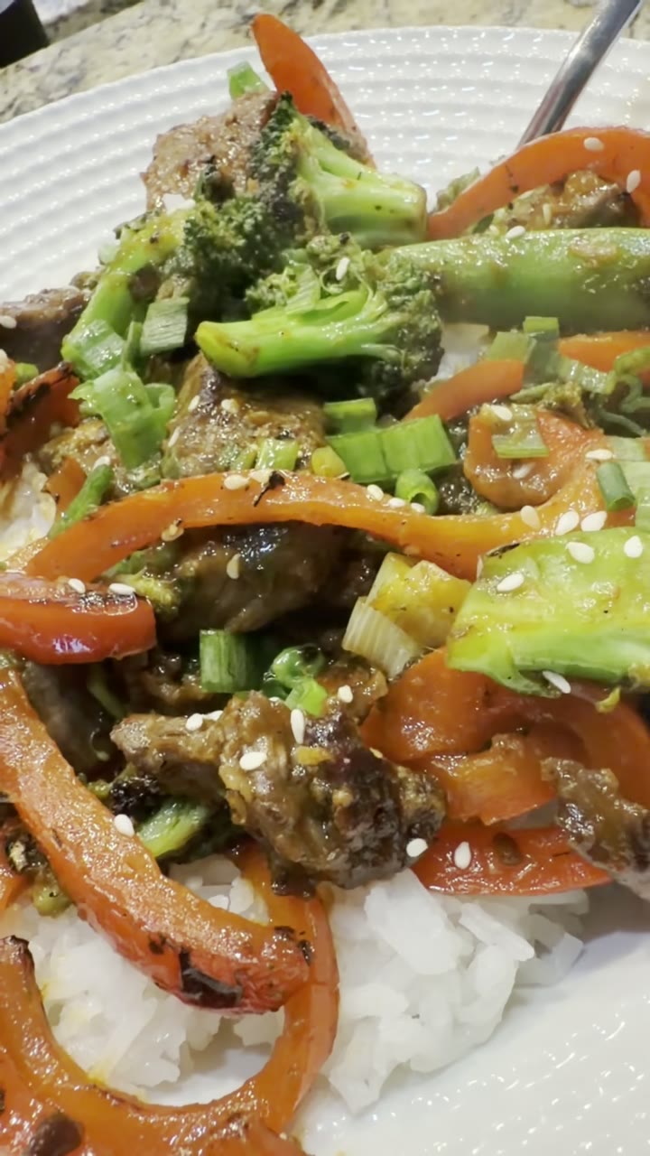 Beef and broccoli stir-fry with bell pepper, scallions, and sesame over white rice