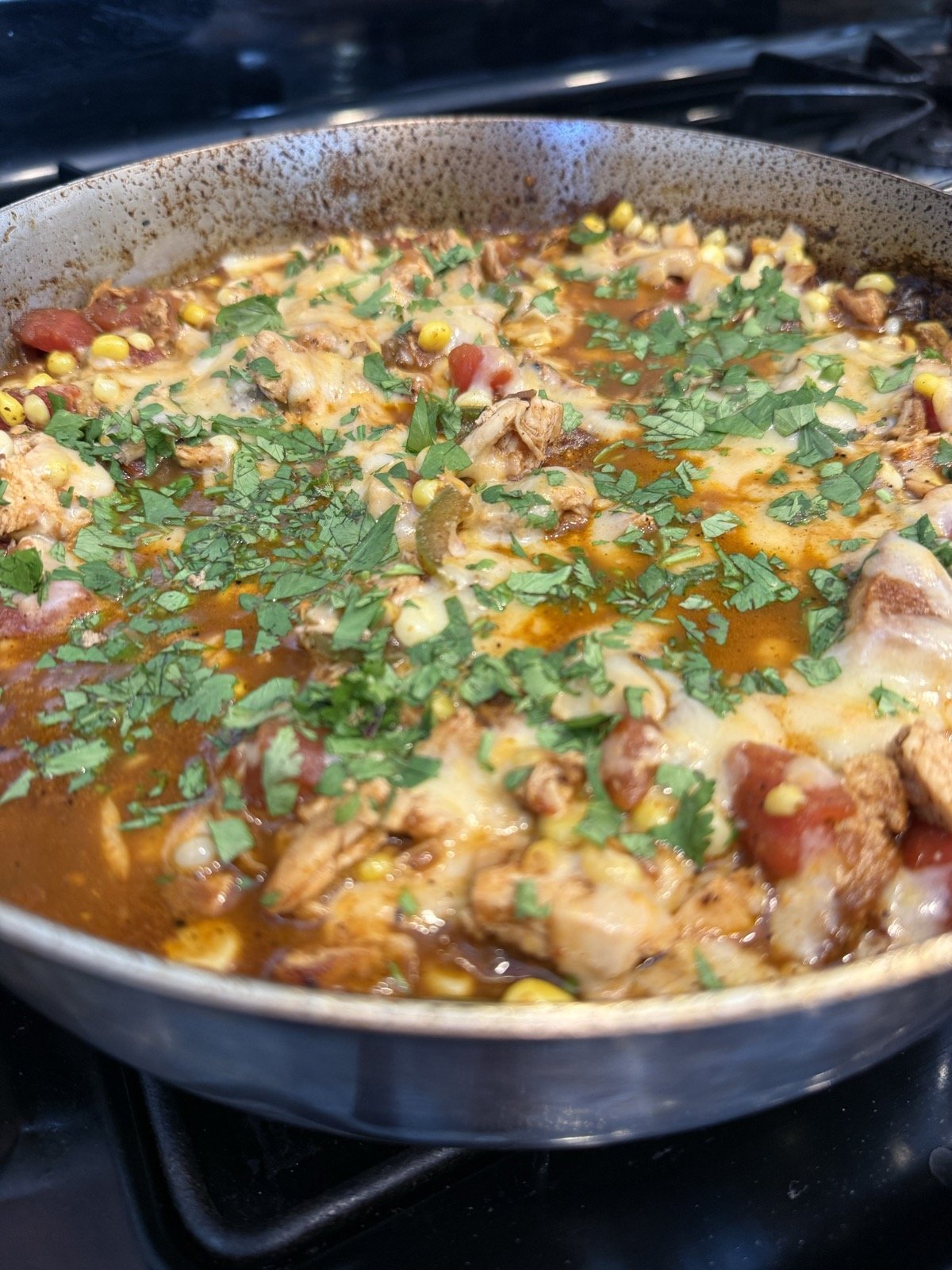 Chicken enchilada skillet with corn, tomatoes, and melted cheddar topped with chopped cilantro