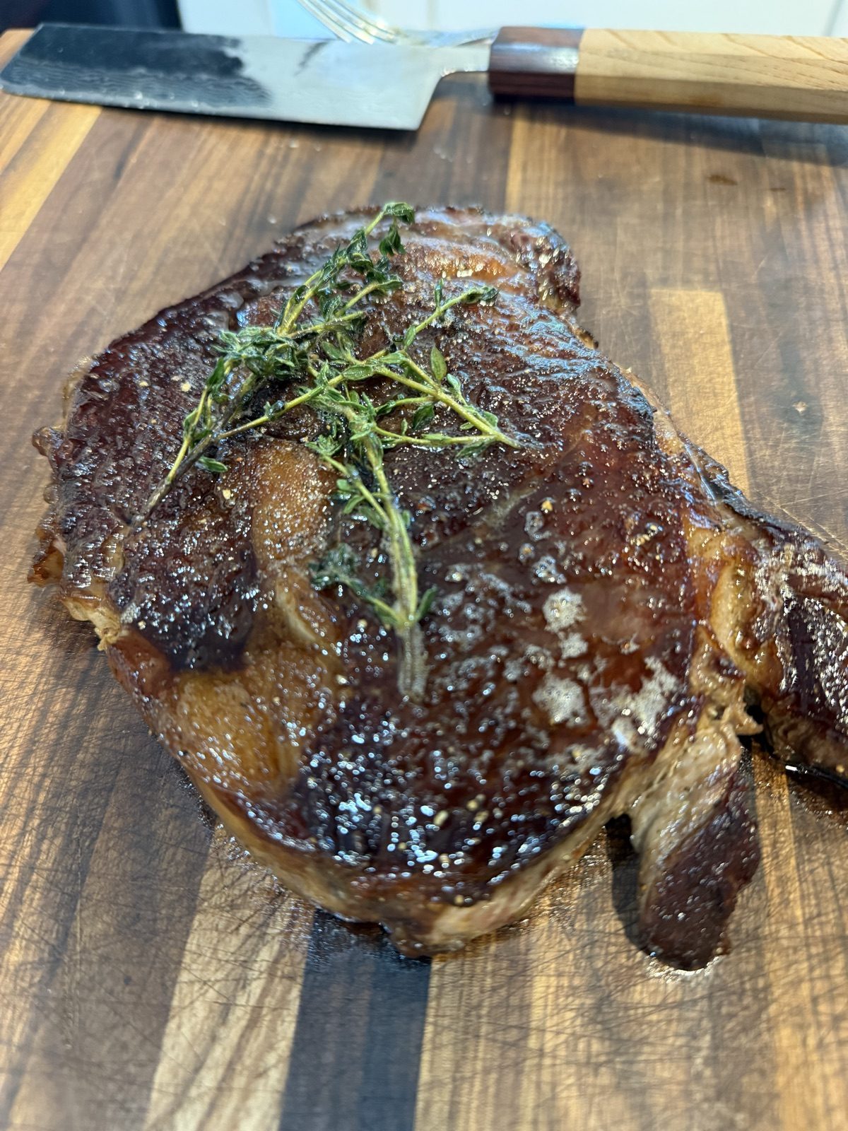 Grilled beef sirloin steak with a charred crust resting on a wooden cutting board