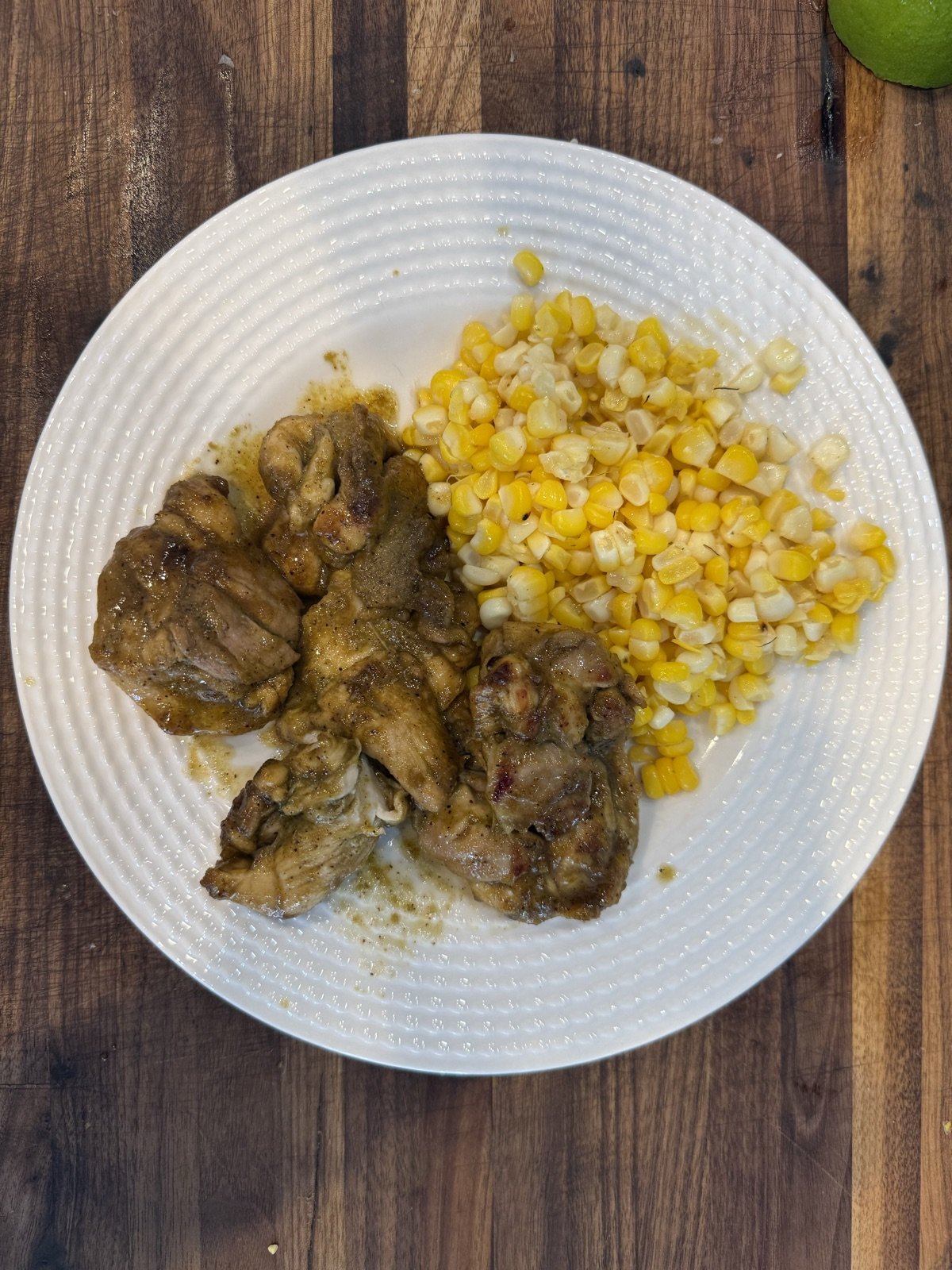 Honey cilantro lime chicken thighs with charred corn on a white plate