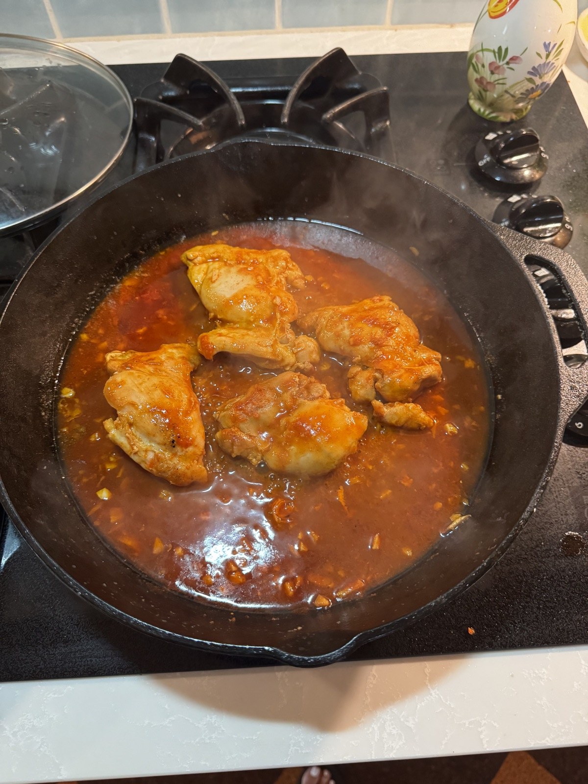 Chicken thighs braising in gochujang glaze in a cast-iron skillet