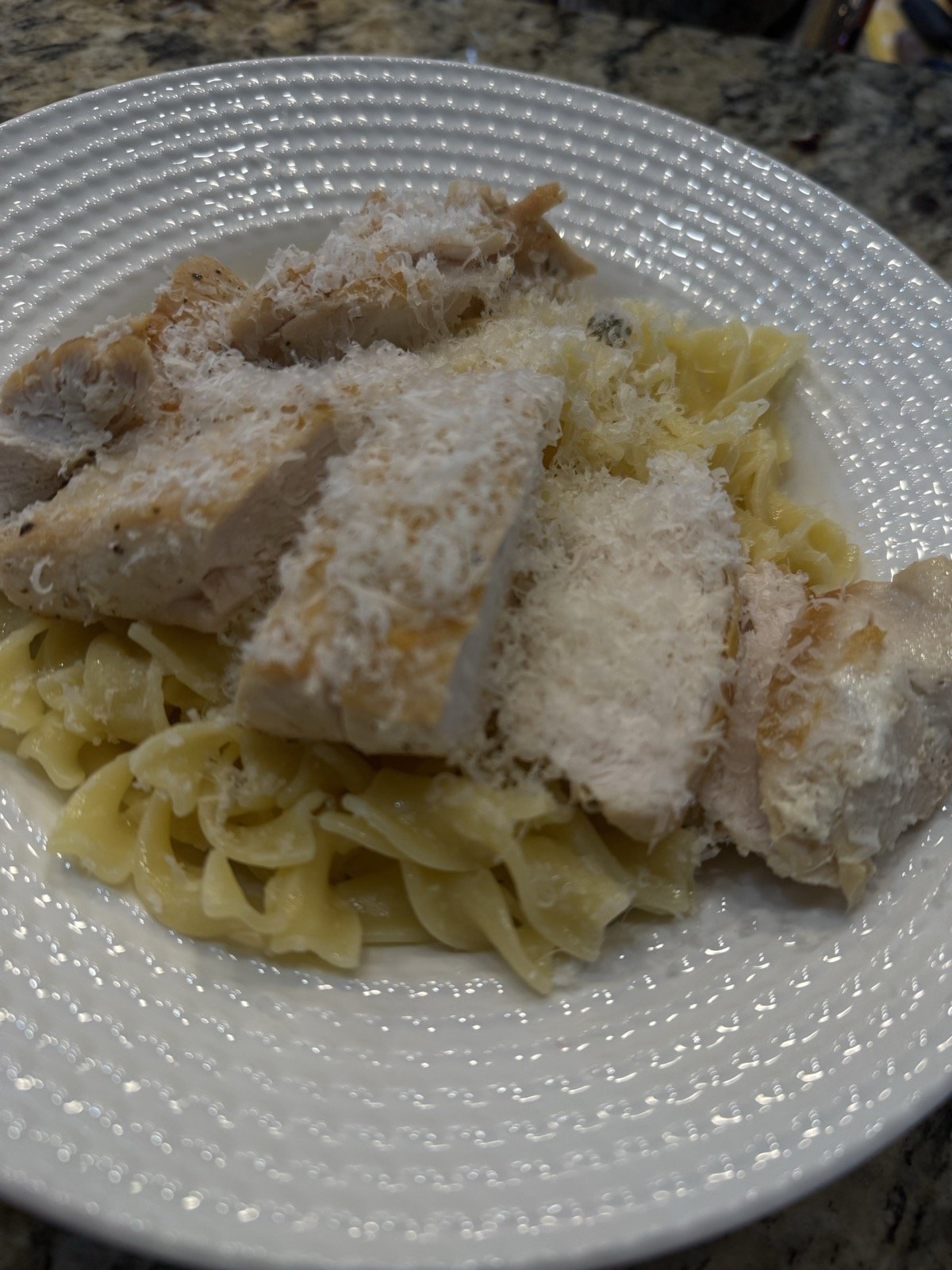 Sliced cast-iron seared chicken breast over buttered egg noodles, topped with finely grated Parmigiano Reggiano